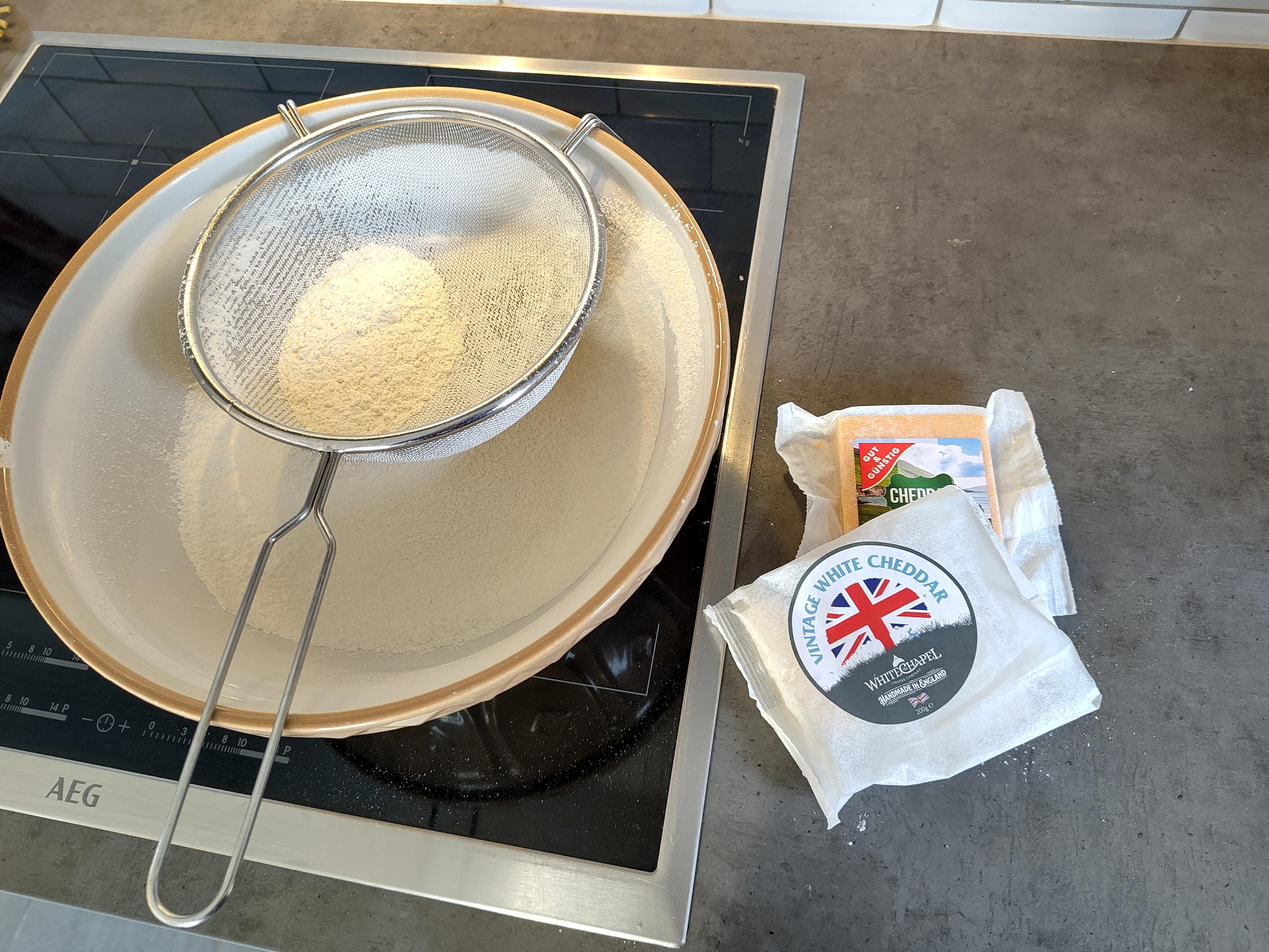 Photo of the ingredients for cheese scones sitting partially used on a kitchen counter.